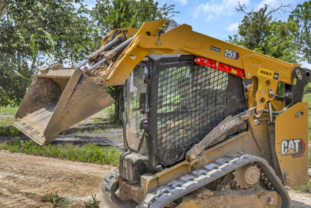 Skid steer loader lifting bucket during excavation and land clearing work on a job site