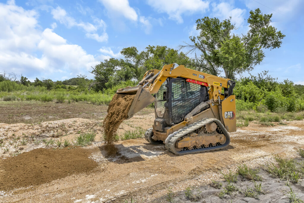 Skid steer dumping soil during land grading and excavation work on a job site