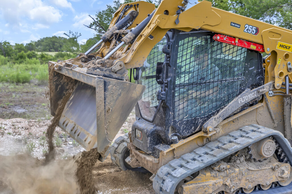 Skid steer loader dumping soil during excavation and land grading work on a construction site